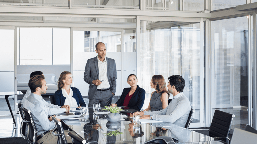 Illustration of a meeting at a boardroom table with the presenter standing up